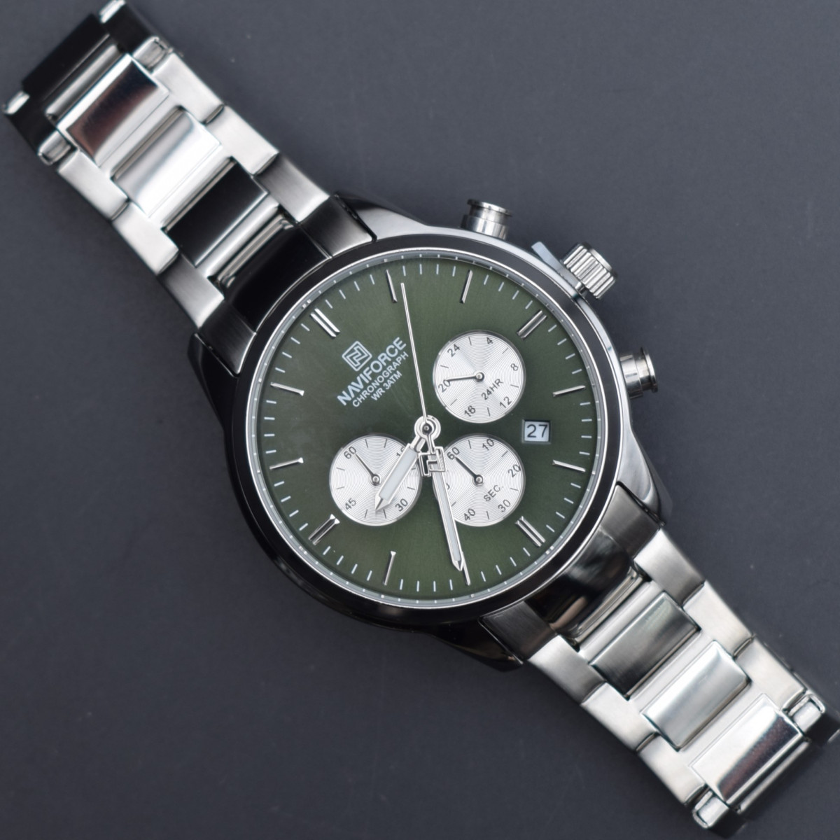 تصویر ساعت نیوی فورس سه موتور مردانه با بند رنگ نقره‌ای و صفحه سبز تیره، طراحی خاص و کیفیت عالی